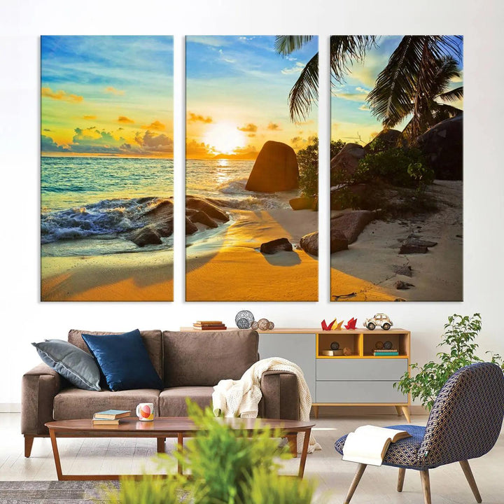 The Serene Tropical Beach Sunset Canvas Wall Art, a 3-panel giclee print, beautifully captures an ocean sunset with its depiction of palm trees and a coastal rock formation.