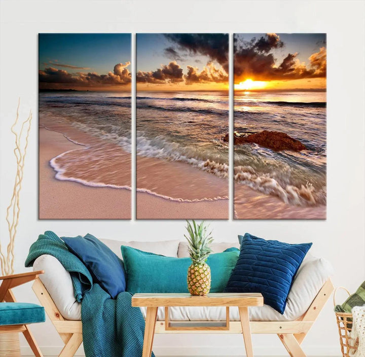 The Sunset Beach Waves Triptych Wall Art, featuring a tropical ocean scene on giclee canvas with a gallery wrap, adorns the wall in a cozy, coastal-themed living room.