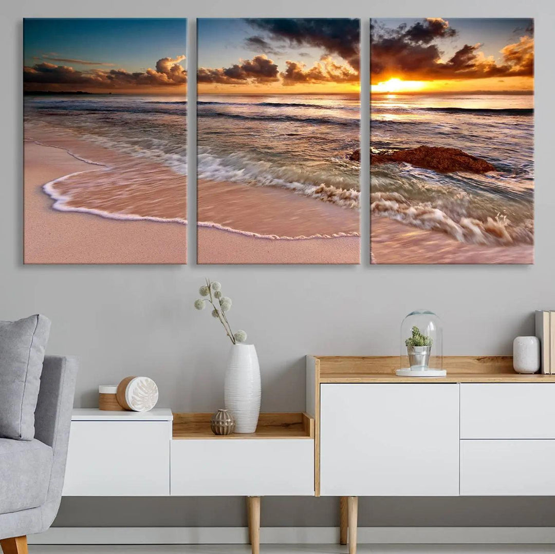 The Sunset Beach Waves Triptych Wall Art, featuring a tropical ocean scene on giclee canvas with a gallery wrap, adorns the wall in a cozy, coastal-themed living room.