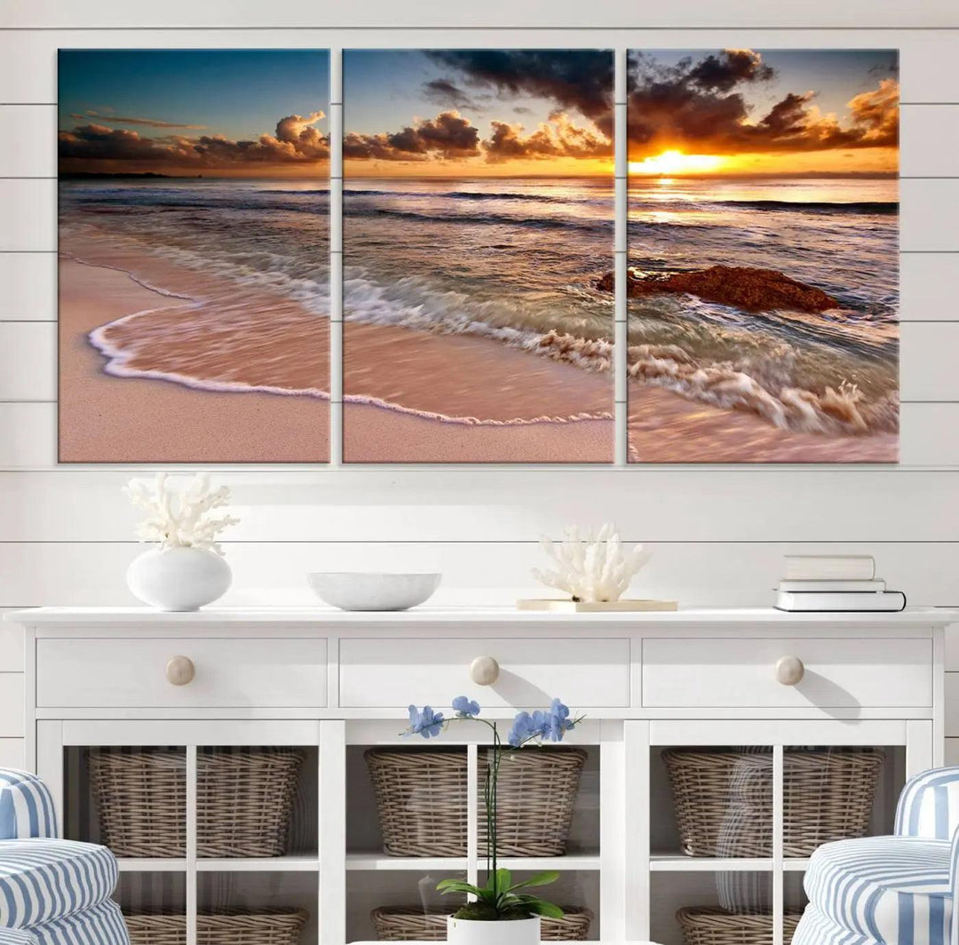 The Sunset Beach Waves Triptych Wall Art, featuring a tropical ocean scene on giclee canvas with a gallery wrap, adorns the wall in a cozy, coastal-themed living room.