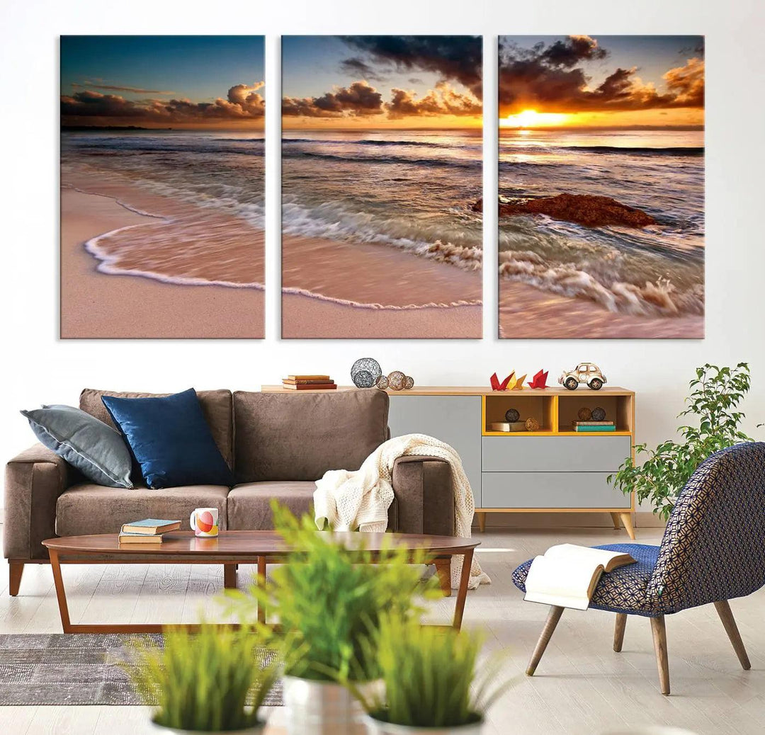 The Sunset Beach Waves Triptych Wall Art, featuring a tropical ocean scene on giclee canvas with a gallery wrap, adorns the wall in a cozy, coastal-themed living room.