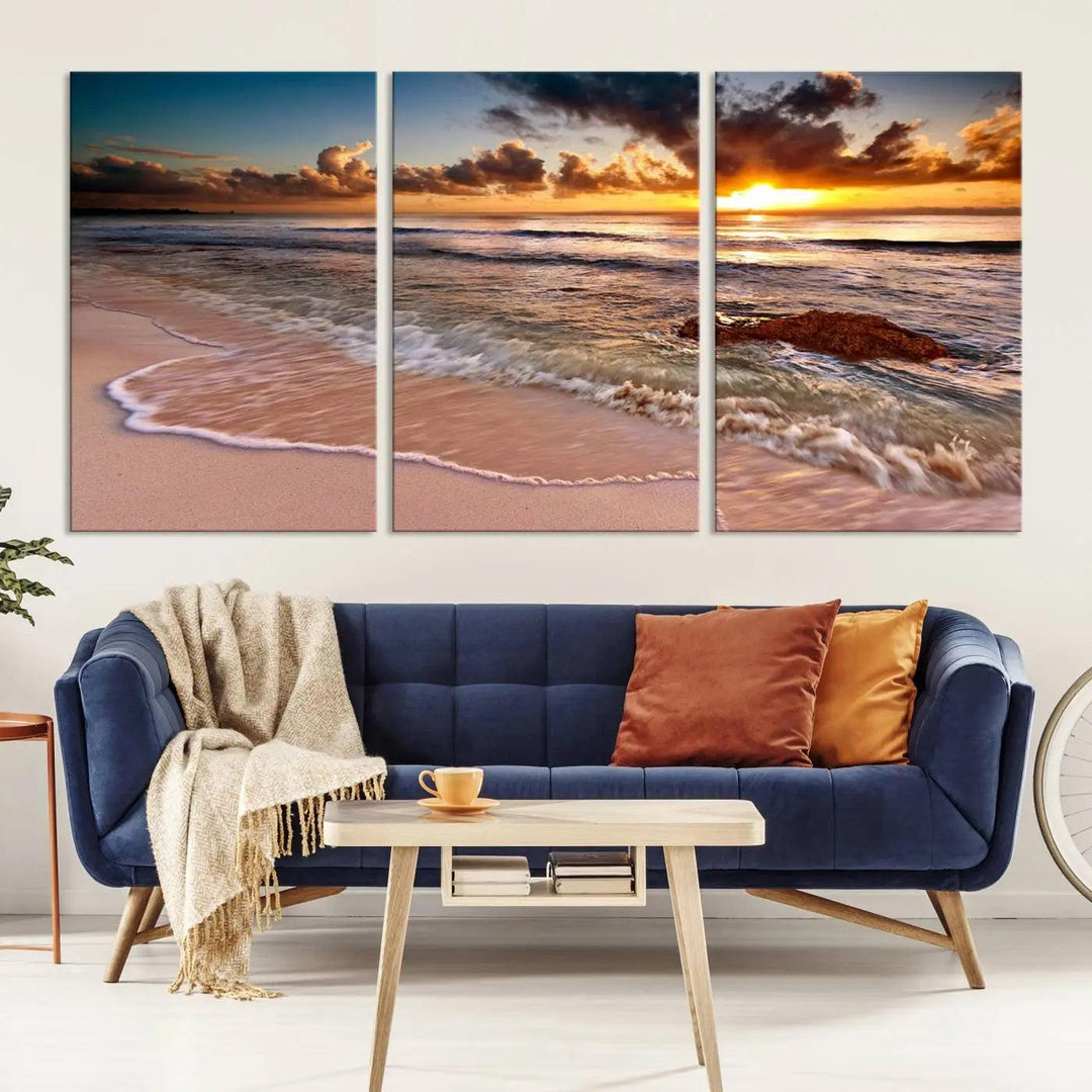 The Sunset Beach Waves Triptych Wall Art, featuring a tropical ocean scene on giclee canvas with a gallery wrap, adorns the wall in a cozy, coastal-themed living room.