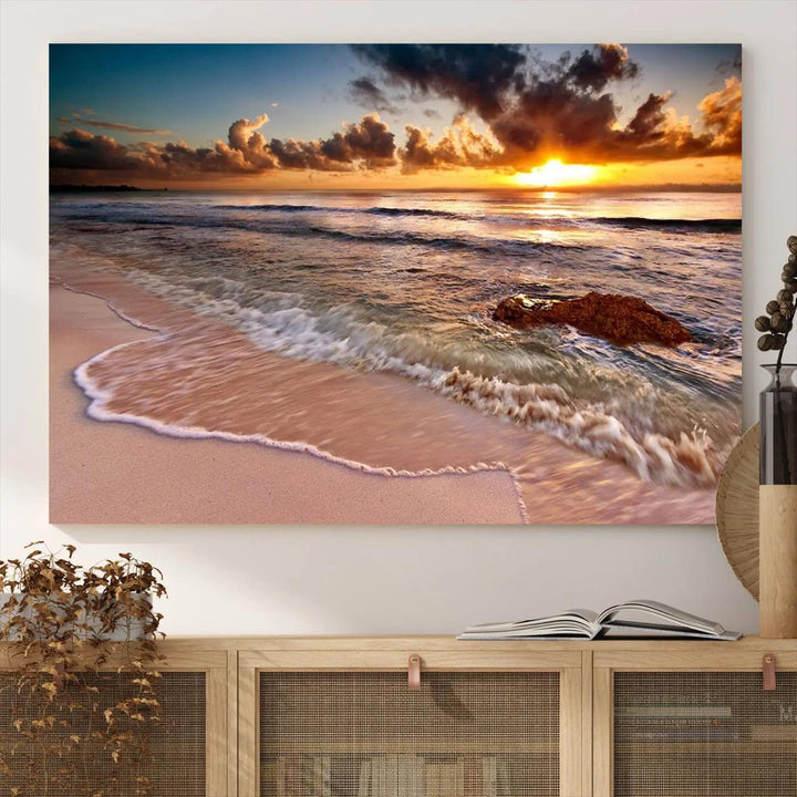 The Sunset Beach Waves Triptych Wall Art, featuring a tropical ocean scene on giclee canvas with a gallery wrap, adorns the wall in a cozy, coastal-themed living room.