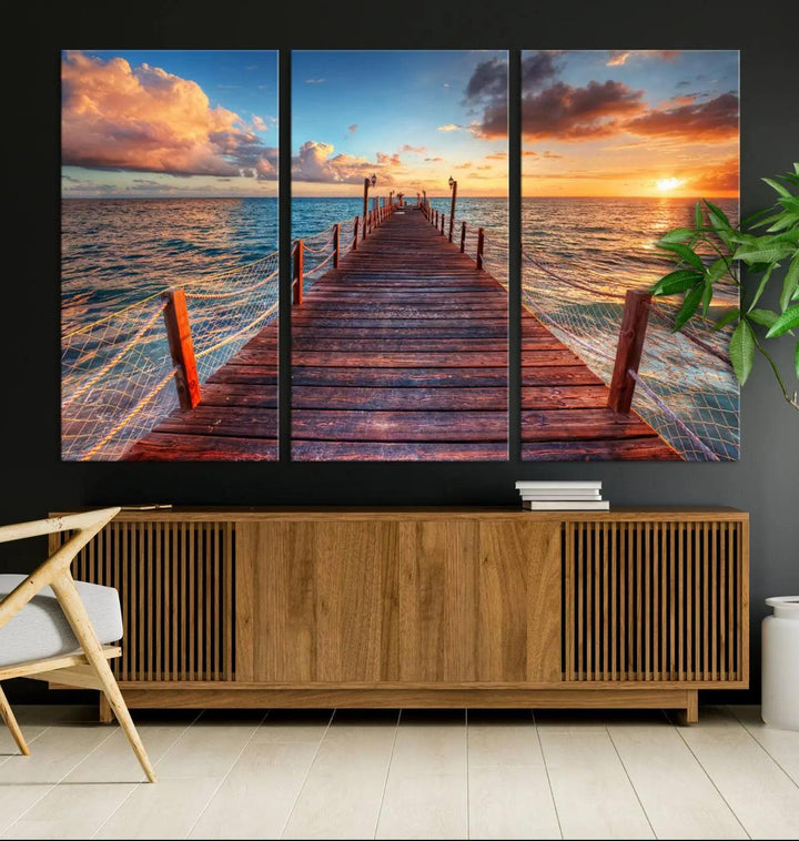 The Sunset Pier Canvas Wall Art is a triptych featuring an ocean landscape that elegantly captures a tranquil beach sunset with gentle ocean waves. It comes beautifully framed and ready to hang.