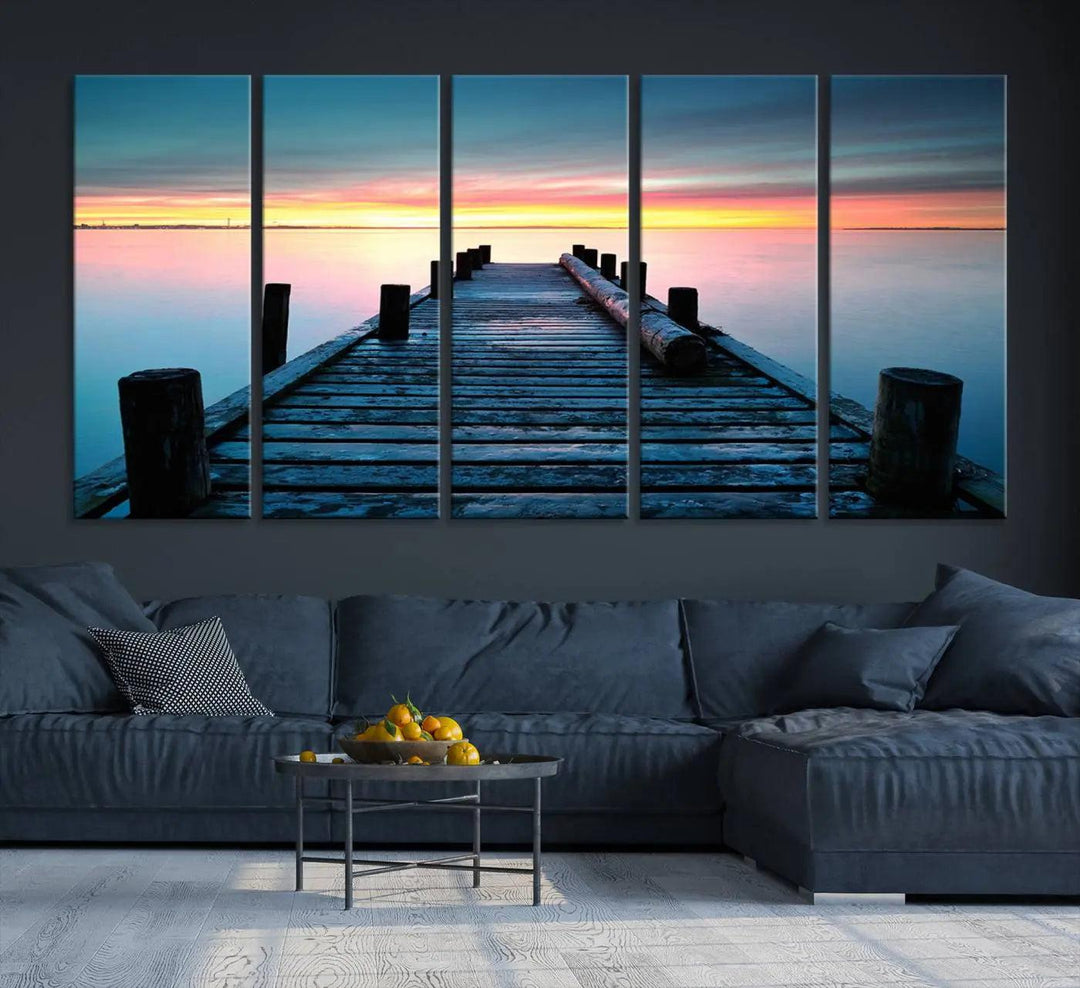 The "Sunset Pier Triptych Canvas Art," a giclee print known for its Canon print quality and gallery wrap finish, captures a wooden pier stretching into a tranquil lake at sunset beneath vibrant orange and blue skies. It makes an ideal centerpiece for coastal-themed art settings.