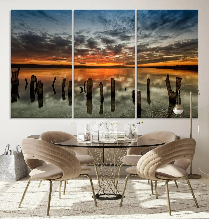 The "Sunset Reflection on Wooden Pier Giclee Canvas Print" is a panoramic wall art piece showcasing serene nature photography with a colorful sunset over water and wooden posts.