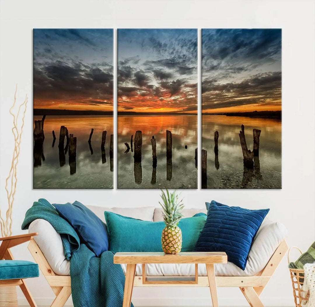 The "Sunset Reflection on Wooden Pier Giclee Canvas Print" is a panoramic wall art piece showcasing serene nature photography with a colorful sunset over water and wooden posts.