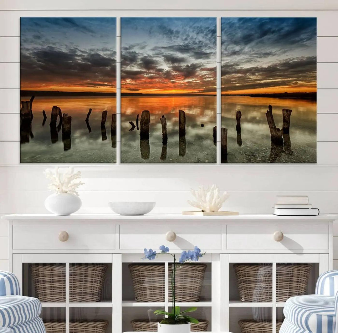 The "Sunset Reflection on Wooden Pier Giclee Canvas Print" is a panoramic wall art piece showcasing serene nature photography with a colorful sunset over water and wooden posts.