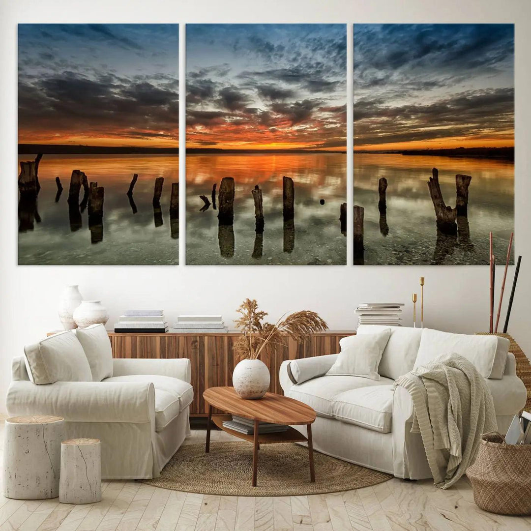 The "Sunset Reflection on Wooden Pier Giclee Canvas Print" is a panoramic wall art piece showcasing serene nature photography with a colorful sunset over water and wooden posts.