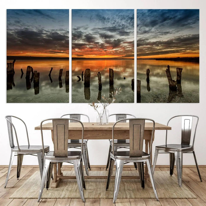 The "Sunset Reflection on Wooden Pier Giclee Canvas Print" is a panoramic wall art piece showcasing serene nature photography with a colorful sunset over water and wooden posts.