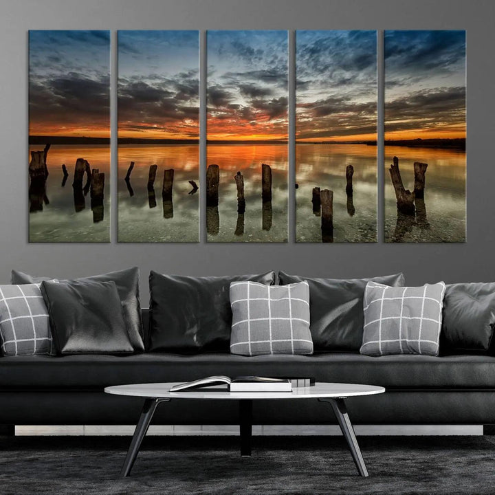 The "Sunset Reflection on Wooden Pier Giclee Canvas Print" is a panoramic wall art piece showcasing serene nature photography with a colorful sunset over water and wooden posts.