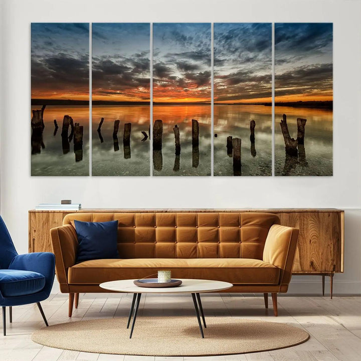 The "Sunset Reflection on Wooden Pier Giclee Canvas Print" is a panoramic wall art piece showcasing serene nature photography with a colorful sunset over water and wooden posts.