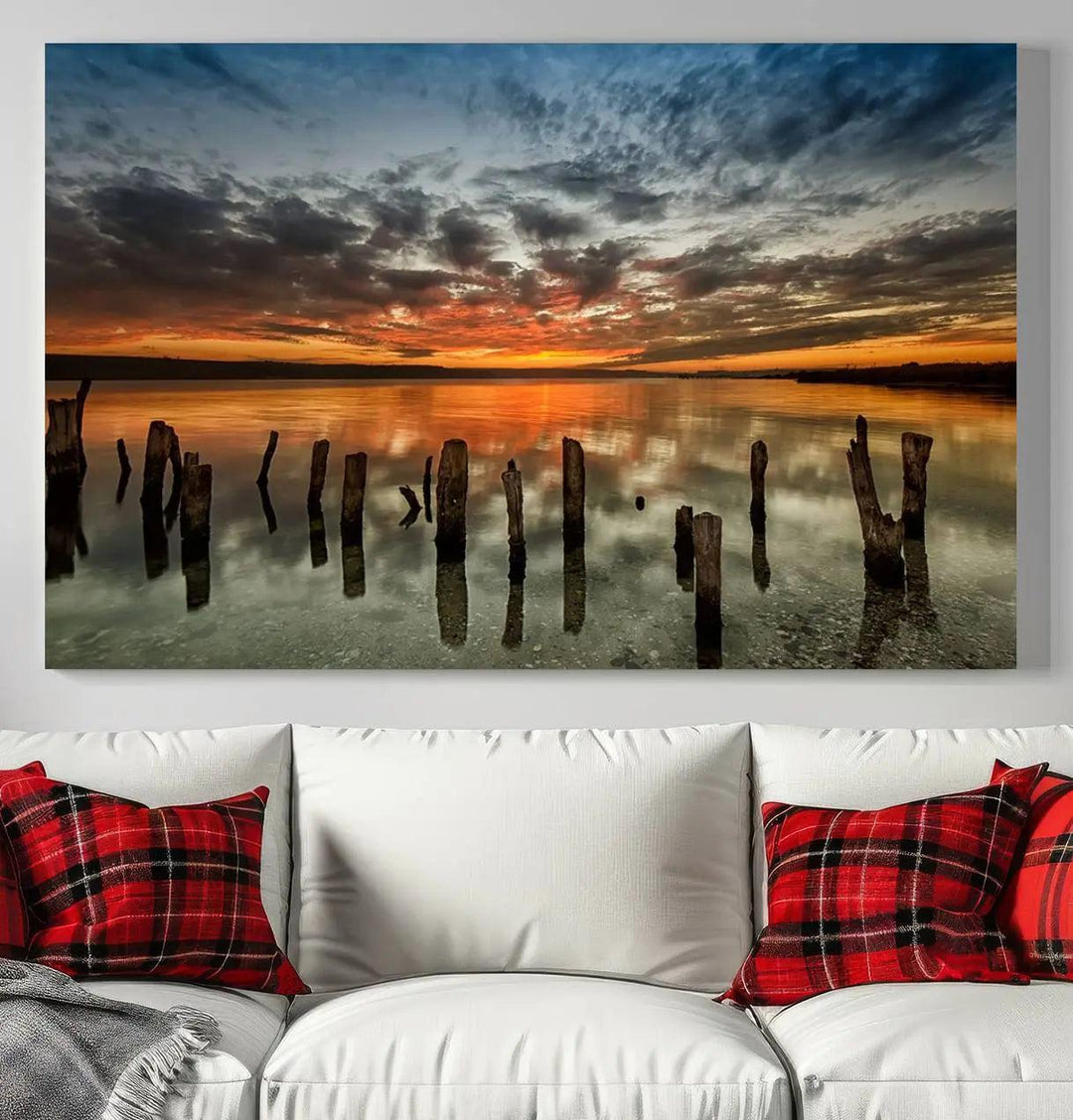 The "Sunset Reflection on Wooden Pier Giclee Canvas Print" is a panoramic wall art piece showcasing serene nature photography with a colorful sunset over water and wooden posts.