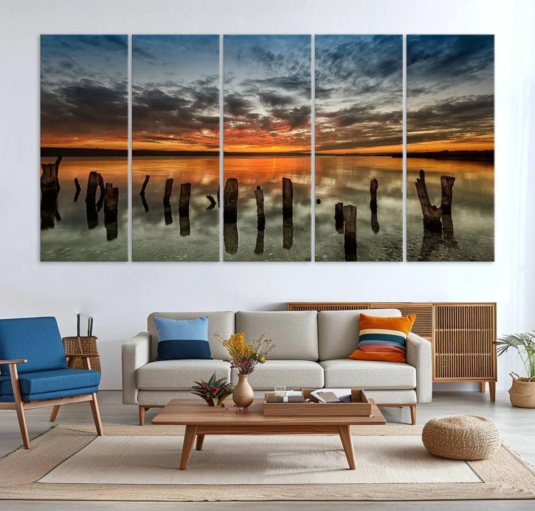 The "Sunset Reflection on Wooden Pier Giclee Canvas Print" is a panoramic wall art piece showcasing serene nature photography with a colorful sunset over water and wooden posts.