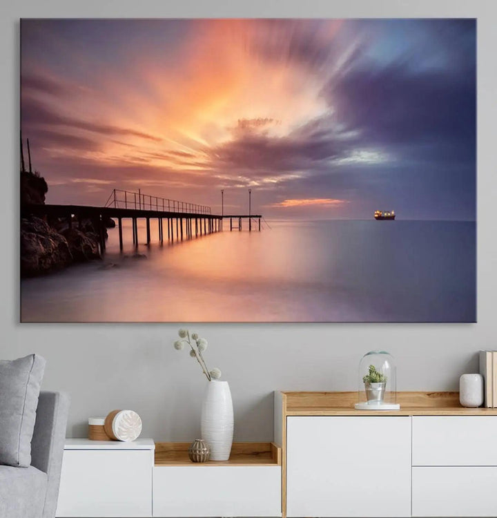 The Sunset Serenity Pier Canvas Art, a giclee canvas print with gallery wrap, beautifully captures a triptych of tranquility as the sun sets over calm waters. Featuring a pier on the left and a ship on the horizon, it adds an elegant touch to any living space with its serene coastal decor.