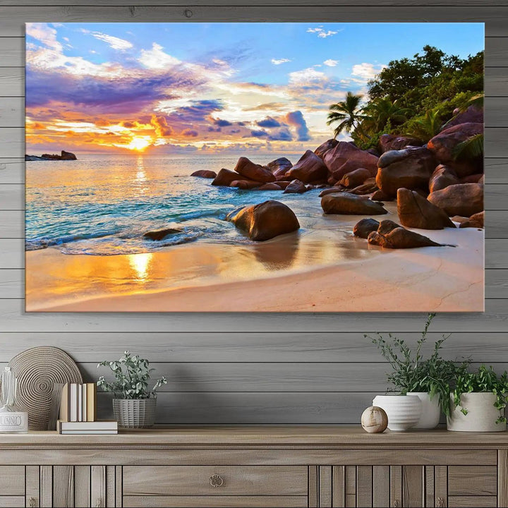 A captivating Tropical Beach Sunset Canvas Print, featuring ocean waves and a rocky shoreline, graces the wall.