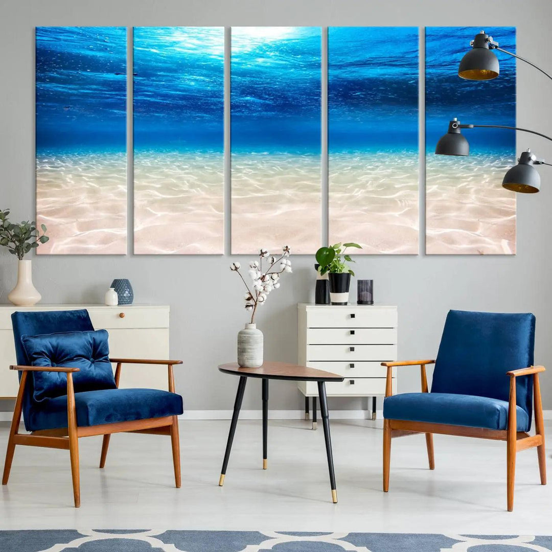 The "Underwater Ocean Scene Giclee Canvas Print – Serene Deep Blue Seascape Wall Art for Coastal Home Decor, Tranquil Sea Bottom Landscape" is gracefully mounted on a wooden wall, creating the perfect marine-themed home decor with its depiction of sunlight illuminating the sandy ocean floor.