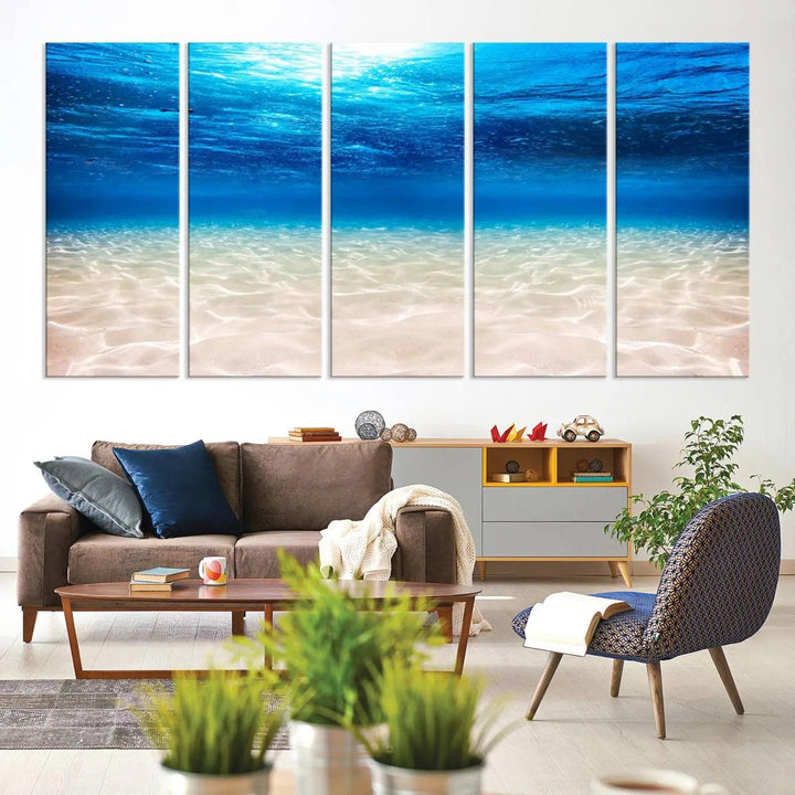 The "Underwater Ocean Scene Giclee Canvas Print – Serene Deep Blue Seascape Wall Art for Coastal Home Decor, Tranquil Sea Bottom Landscape" is gracefully mounted on a wooden wall, creating the perfect marine-themed home decor with its depiction of sunlight illuminating the sandy ocean floor.