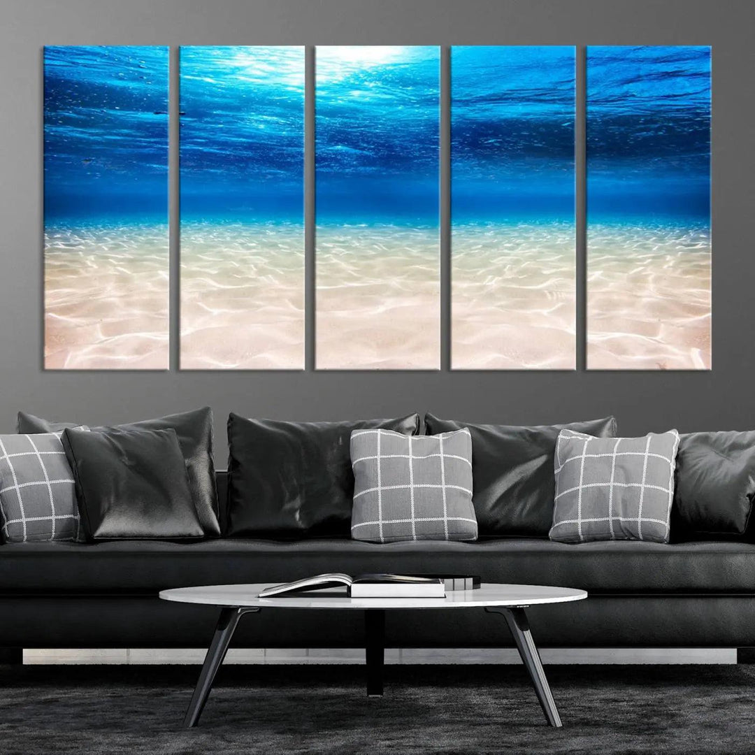 The "Underwater Ocean Scene Giclee Canvas Print – Serene Deep Blue Seascape Wall Art for Coastal Home Decor, Tranquil Sea Bottom Landscape" is gracefully mounted on a wooden wall, creating the perfect marine-themed home decor with its depiction of sunlight illuminating the sandy ocean floor.