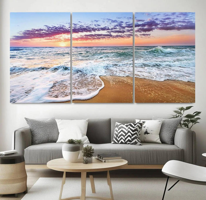 The "Vivid Sunset Ocean Waves Wall Art" hangs on the wall, capturing the serene beauty of the sea. This coastal beach canvas print triptych perfectly enhances living rooms and relaxation spaces.