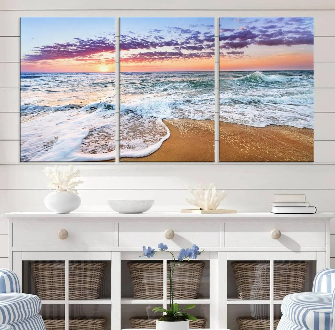 The "Vivid Sunset Ocean Waves Wall Art" hangs on the wall, capturing the serene beauty of the sea. This coastal beach canvas print triptych perfectly enhances living rooms and relaxation spaces.