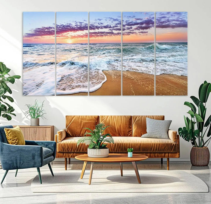 The "Vivid Sunset Ocean Waves Wall Art" hangs on the wall, capturing the serene beauty of the sea. This coastal beach canvas print triptych perfectly enhances living rooms and relaxation spaces.