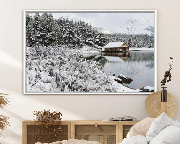 Experience the beauty of winter with the "Cabin by the Lake Canvas Wall Art," showcasing a serene snowy landscape. This rustic nature decor features a cozy cabin nestled amid snow-laden trees, set against a breathtaking mountain view, perfect for enhancing your living room.