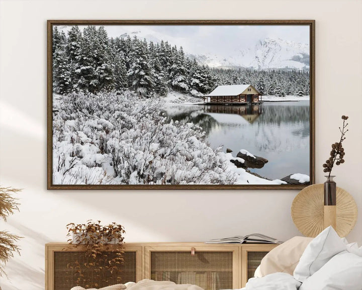 Experience the beauty of winter with the "Cabin by the Lake Canvas Wall Art," showcasing a serene snowy landscape. This rustic nature decor features a cozy cabin nestled amid snow-laden trees, set against a breathtaking mountain view, perfect for enhancing your living room.