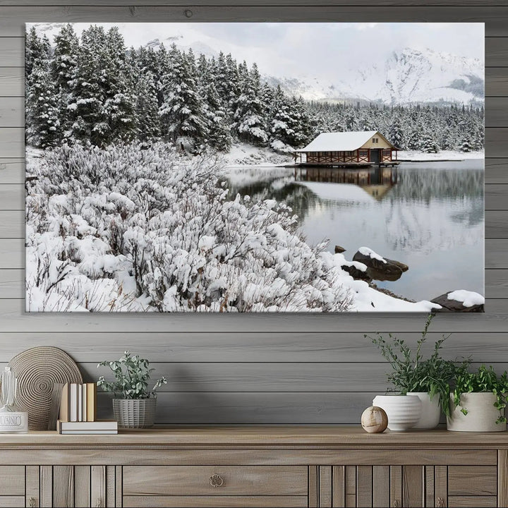 Experience the beauty of winter with the "Cabin by the Lake Canvas Wall Art," showcasing a serene snowy landscape. This rustic nature decor features a cozy cabin nestled amid snow-laden trees, set against a breathtaking mountain view, perfect for enhancing your living room.